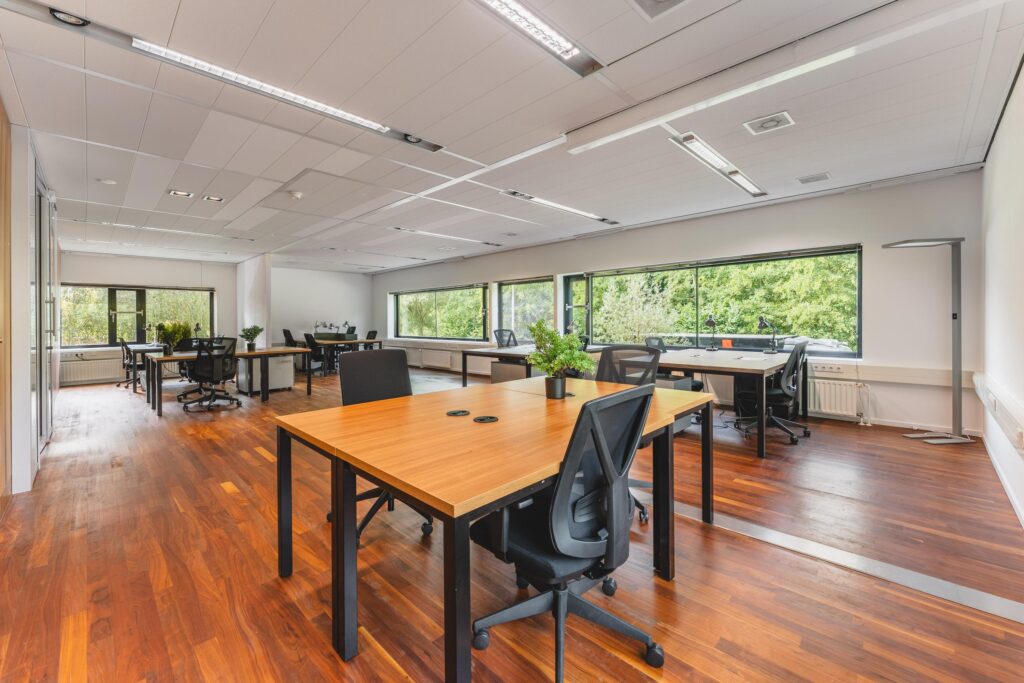 Modern en licht kantoor met houten vloer, grote ramen en meerdere werkplekken aan de Prof. W.H. Keesomlaan.